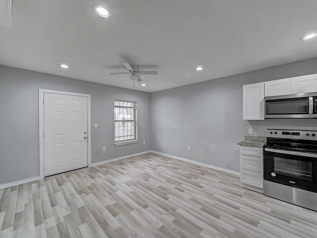 kitchen with light stone counters, stainless steel appliances, ceiling fan, light hardwood / wood-style flooring, and white cabinets