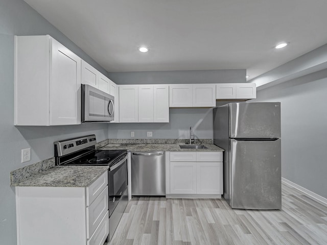 kitchen featuring sink, light stone countertops, light hardwood / wood-style floors, white cabinetry, and stainless steel appliances