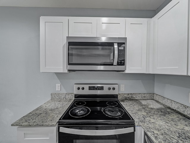 kitchen with light stone countertops, white cabinets, and appliances with stainless steel finishes