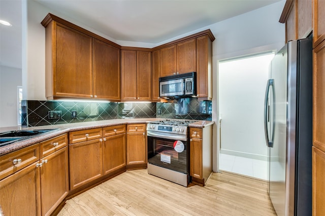 kitchen with decorative backsplash, light wood-type flooring, and stainless steel appliances