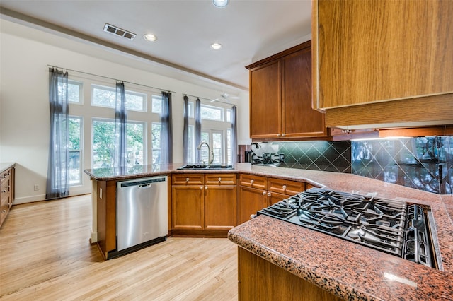 kitchen featuring sink, decorative backsplash, stainless steel dishwasher, kitchen peninsula, and light wood-type flooring