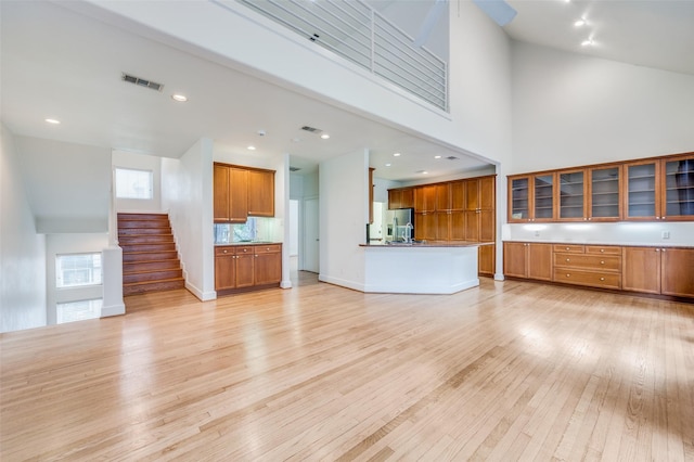 unfurnished living room with light hardwood / wood-style floors and a high ceiling