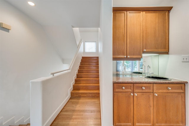 kitchen featuring light stone counters, sink, and light wood-type flooring