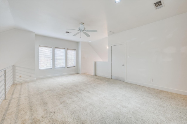 empty room with light colored carpet, vaulted ceiling, and ceiling fan