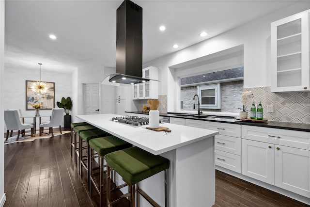 kitchen with white cabinets, a breakfast bar area, a kitchen island, dark hardwood / wood-style flooring, and island exhaust hood