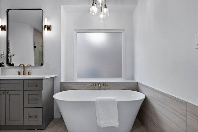 bathroom featuring a tub to relax in, vanity, and tile walls