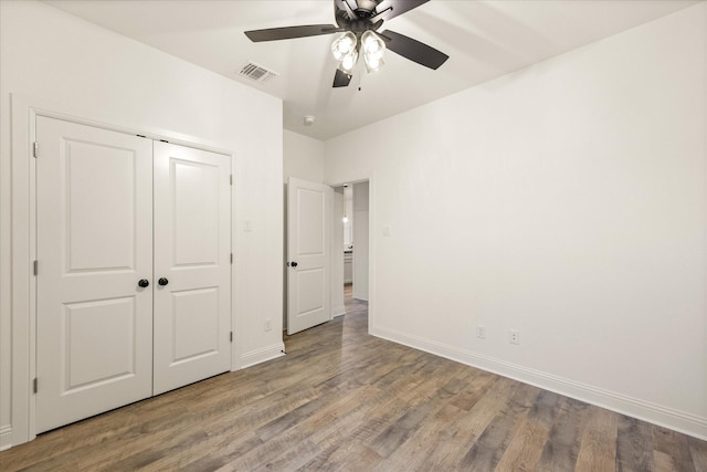 unfurnished bedroom featuring ceiling fan, wood-type flooring, and a closet