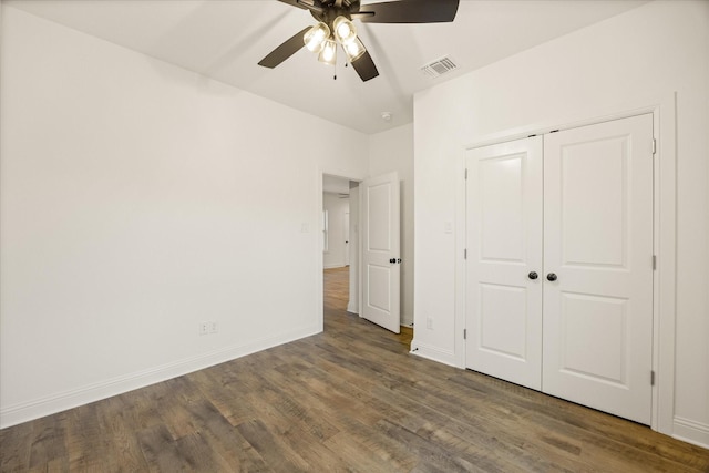 unfurnished bedroom featuring ceiling fan, dark hardwood / wood-style flooring, and a closet