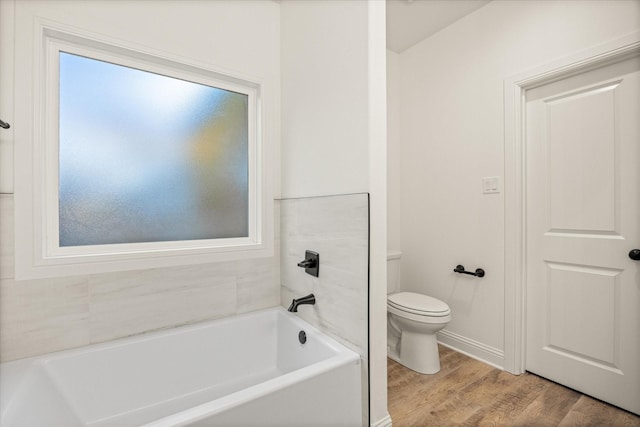 bathroom featuring a bath, hardwood / wood-style flooring, a wealth of natural light, and toilet