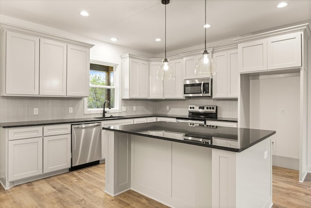 kitchen featuring a kitchen island, decorative light fixtures, white cabinetry, sink, and stainless steel appliances