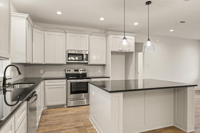 kitchen featuring hanging light fixtures, appliances with stainless steel finishes, and white cabinets