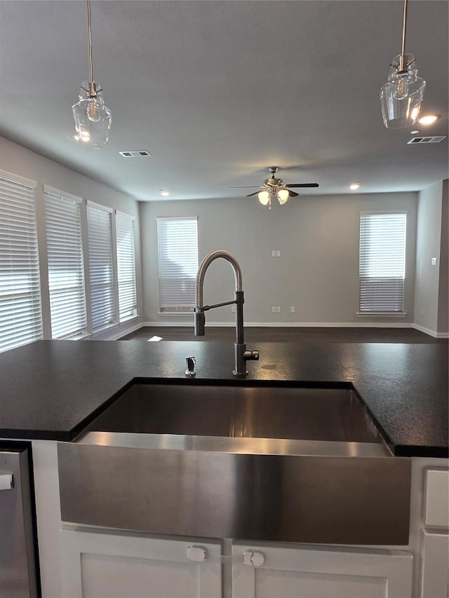 kitchen with decorative light fixtures, dishwasher, sink, and white cabinets