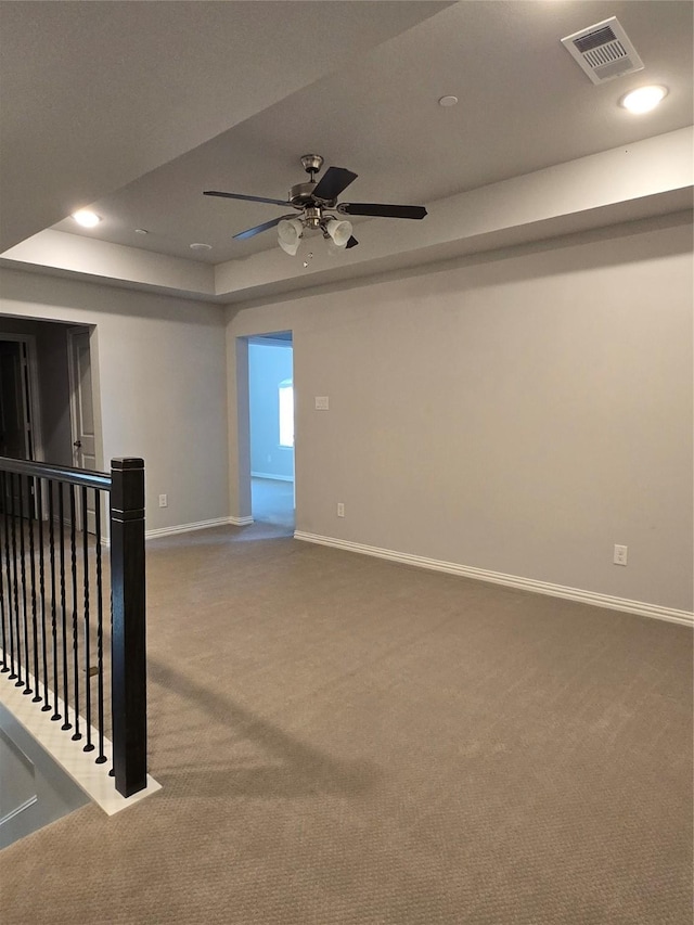 carpeted empty room with a raised ceiling and ceiling fan