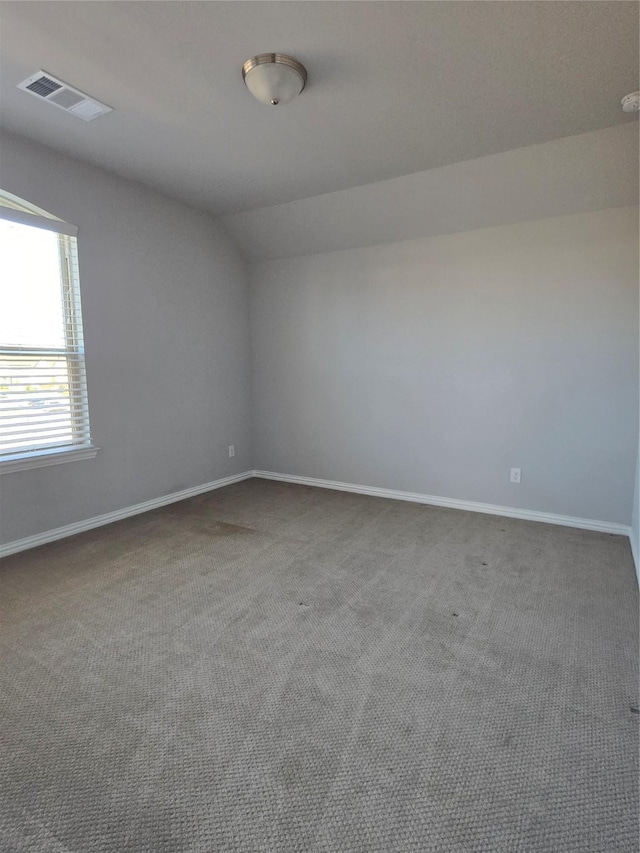 spare room with vaulted ceiling and carpet flooring