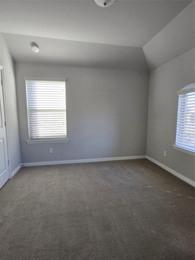 carpeted spare room featuring vaulted ceiling