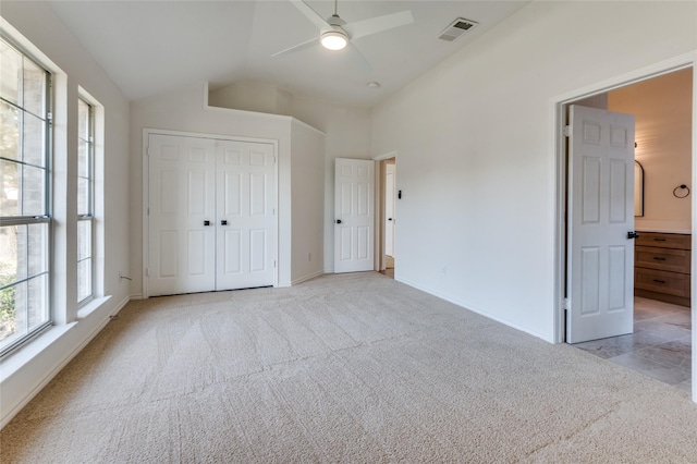 unfurnished bedroom featuring a closet, light colored carpet, vaulted ceiling, and ceiling fan