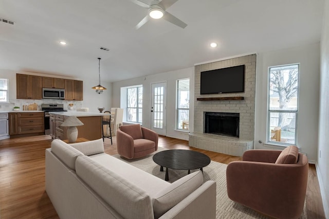 living room featuring ceiling fan, a fireplace, and light hardwood / wood-style floors