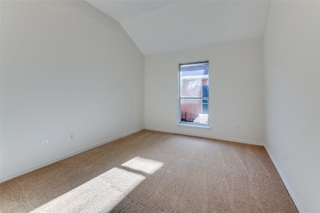 spare room with carpet floors and vaulted ceiling