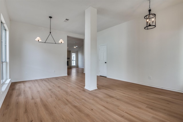 unfurnished dining area with ceiling fan with notable chandelier and light hardwood / wood-style flooring