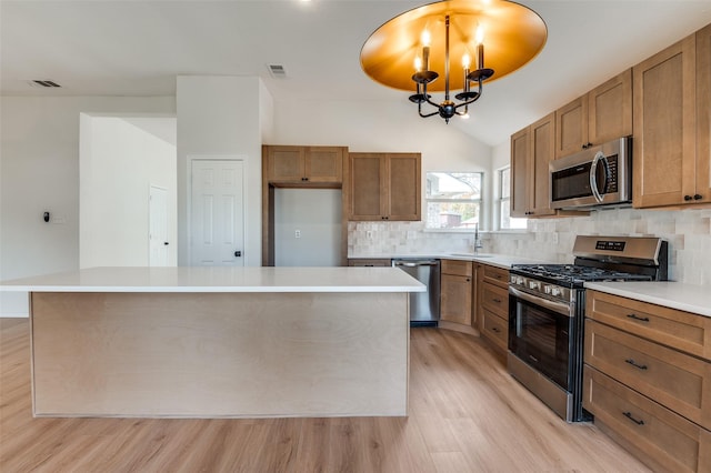 kitchen featuring lofted ceiling, an inviting chandelier, light hardwood / wood-style floors, a kitchen island, and stainless steel appliances