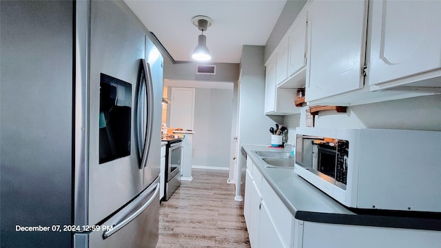 kitchen with pendant lighting, stainless steel appliances, sink, and white cabinets