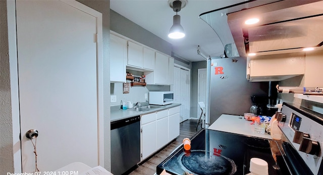 kitchen with sink, white cabinetry, stainless steel dishwasher, pendant lighting, and hardwood / wood-style floors