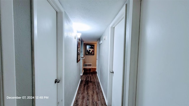 hallway with dark wood-type flooring and a textured ceiling