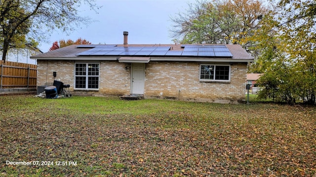 rear view of house with a yard and solar panels