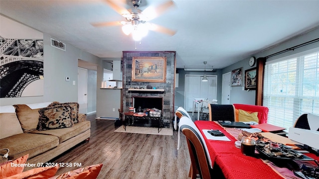 dining space featuring ceiling fan, a stone fireplace, and hardwood / wood-style floors