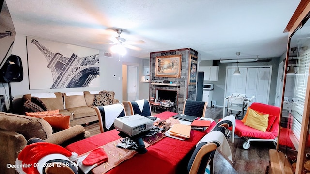 living room with a stone fireplace, hardwood / wood-style floors, and ceiling fan