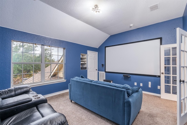 carpeted home theater with vaulted ceiling, french doors, and a textured ceiling