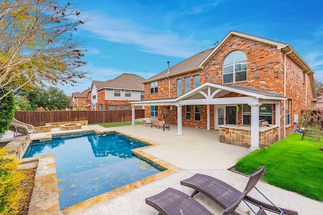 back of property with a fenced in pool, an outdoor bar, a patio, and a lawn