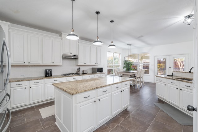 kitchen with appliances with stainless steel finishes, decorative light fixtures, sink, and white cabinets