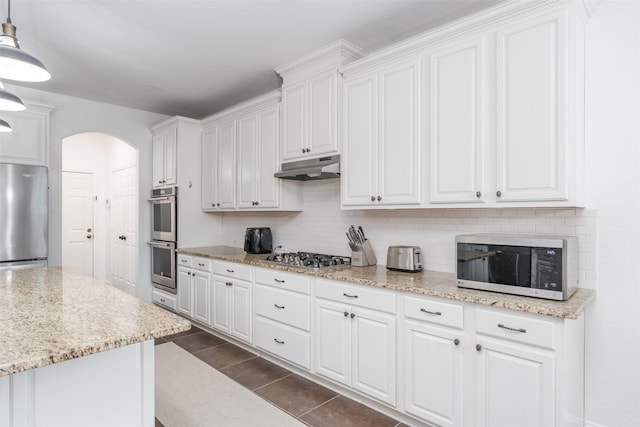 kitchen featuring stainless steel appliances, white cabinets, light stone counters, and decorative light fixtures