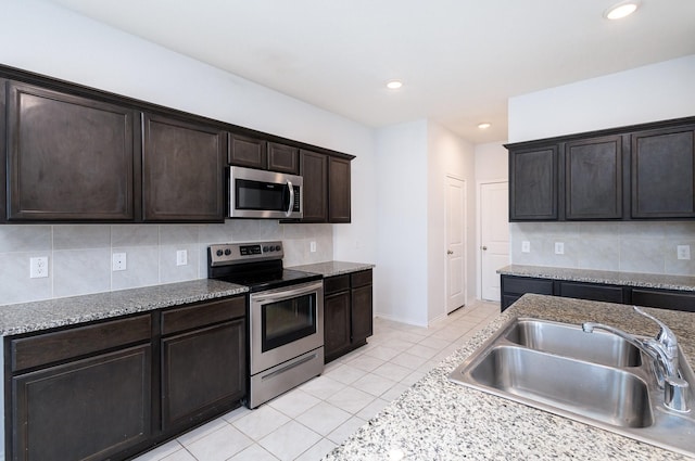 kitchen with decorative backsplash, appliances with stainless steel finishes, dark brown cabinets, sink, and light tile patterned floors