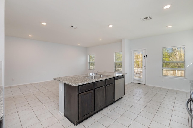 kitchen with sink, light tile patterned floors, dark brown cabinets, an island with sink, and stainless steel dishwasher