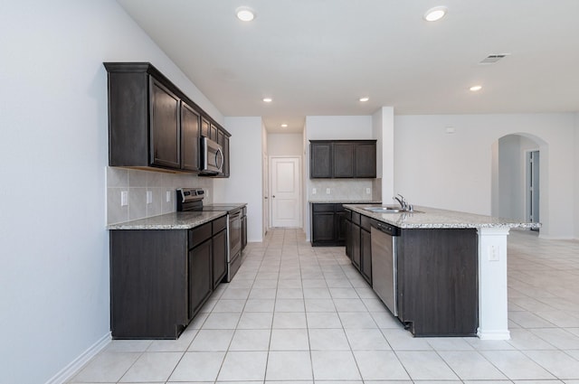 kitchen featuring a kitchen island with sink, sink, dark brown cabinets, and stainless steel appliances