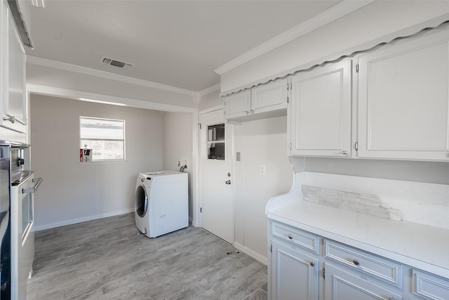 clothes washing area featuring crown molding, light hardwood / wood-style flooring, and washer / dryer