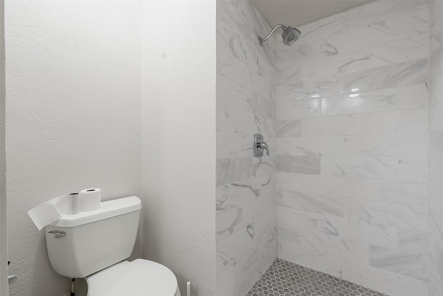 bathroom with a tile shower and toilet