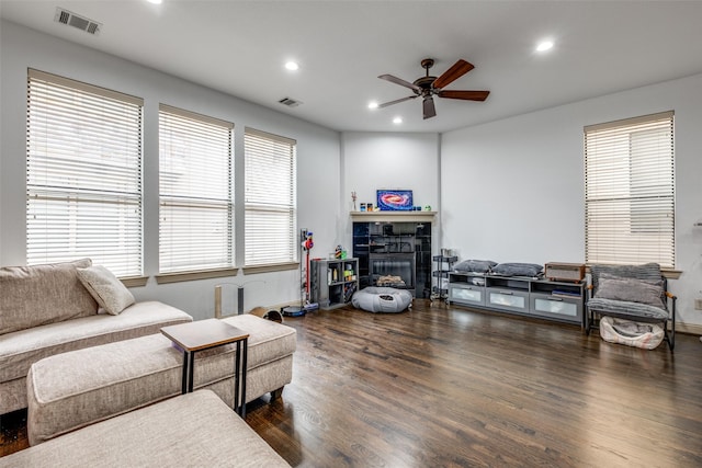 living room featuring a fireplace, ceiling fan, plenty of natural light, and dark wood-type flooring