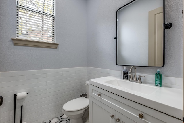 bathroom featuring vanity, toilet, and tile walls