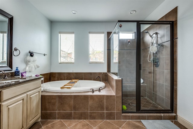 bathroom with tile patterned floors, vanity, a healthy amount of sunlight, and plus walk in shower