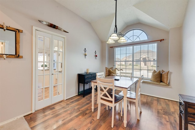 dining room with a notable chandelier, french doors, lofted ceiling, and hardwood / wood-style flooring