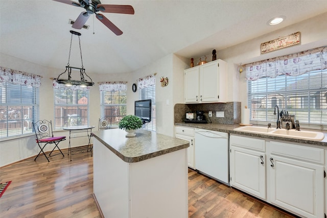 kitchen with white dishwasher, sink, pendant lighting, white cabinets, and a kitchen island