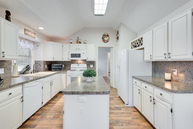 kitchen with a center island, white appliances, sink, vaulted ceiling, and white cabinetry