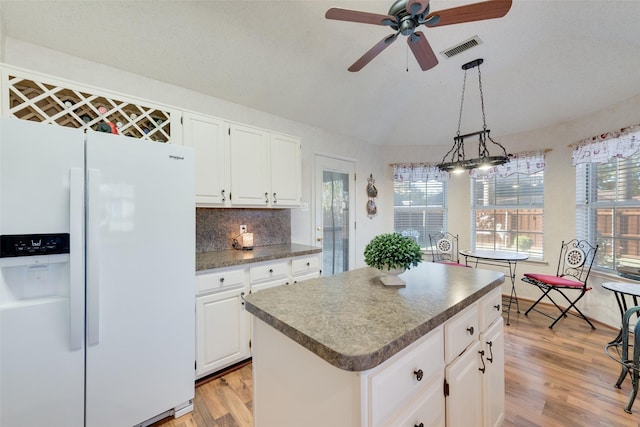 kitchen with pendant lighting, a center island, white fridge with ice dispenser, and white cabinetry