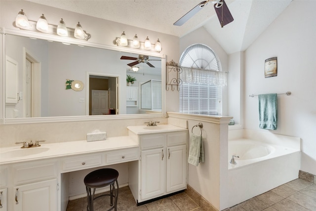 bathroom featuring a bathtub, vanity, vaulted ceiling, tile patterned flooring, and a textured ceiling