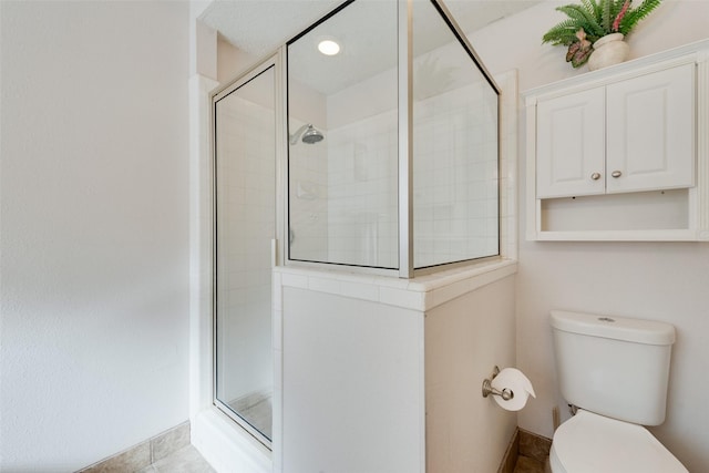 bathroom featuring tile patterned floors, toilet, and a shower with shower door