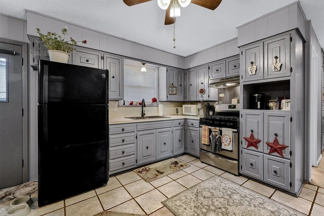 kitchen featuring gray cabinetry, black refrigerator, stainless steel range with gas cooktop, and sink