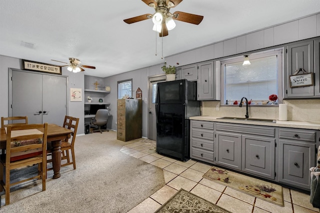 kitchen with gray cabinetry, ceiling fan, sink, tasteful backsplash, and black fridge